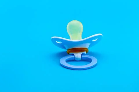 Blue pacifier made of soft silicone  isolated on blue background back view. Stock Photos