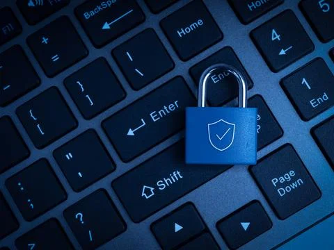 Blue padlock with shield symbol rests on computer keyboard background. Secu.. Stock Photos