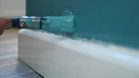 Blue paint is applied on a wall next to a skirting board 動画素材 100975492