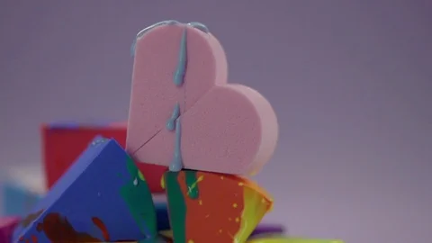 Blue paint drips onto a pink sponge in the shape of a heart. Stock Footage 77512147
