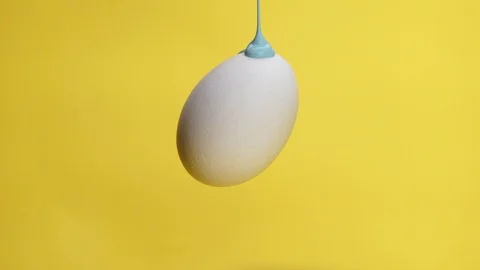 Blue paint flowing on egg howering in air Stock Footage 104569056