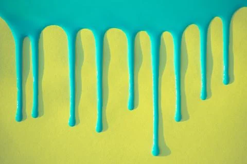 Blue paint flows down on a yellow background. Stock Photos