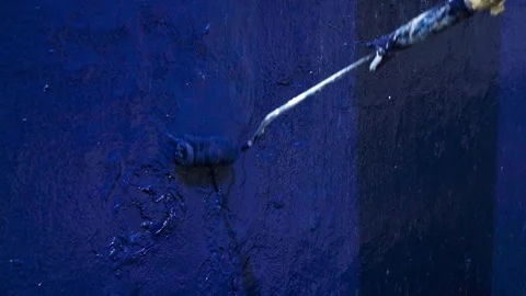Blue paint roller coating rough old ship hull during marine maintenance Stock Footage 338357575