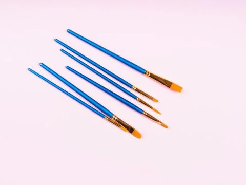 Blue paintbrushes on pink background Stock Photos