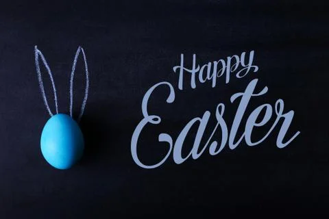 A blue painted Easter egg on a chalkboard with pressed ears looks like a rabb Stock Photos