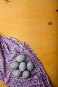 Blue painted Easter eggs on purple towel on yellow bright background Top view Stock Photos