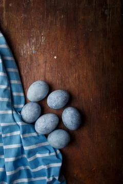 Blue painted easter eggs, some blue striped fabric on brown rustic table Stock Photos