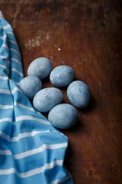 Blue painted easter eggs, some blue striped fabric on brown rustic table Stock Photos