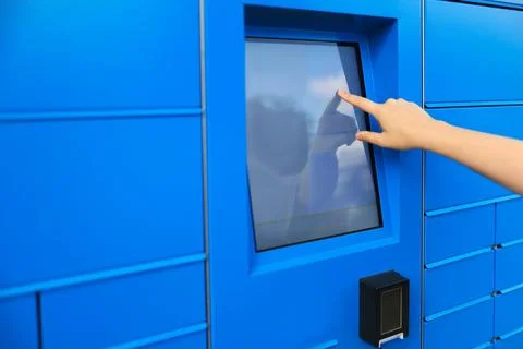 A blue parcel machine designed for receiving packages. A hand is interactin.. Stock Photos
