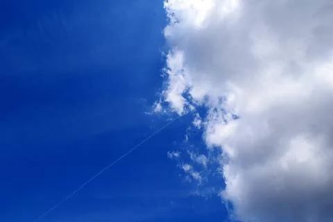 Blue partly cloudy sky with trace of a plane Stock Photos