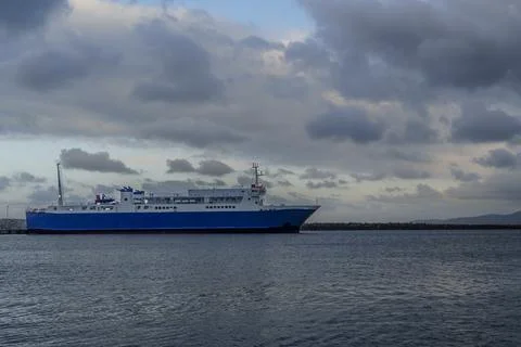 Blue passenger ferry under dramatic cloudy sky Stock Photos