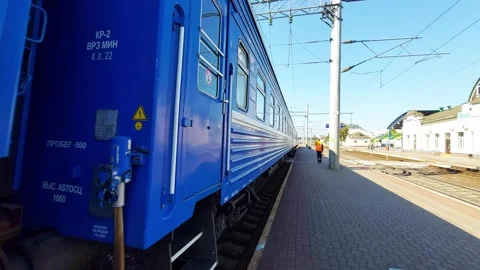 Blue passenger train passes the platform of a railway station in summer. Copy Stock Footage 303620996