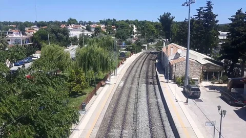 Blue passenger train passing under pedestrian bridge at old train station Stock Footage 93667549