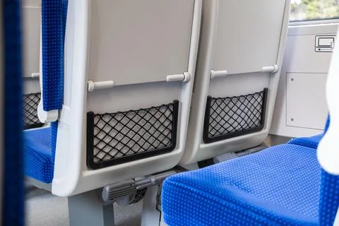 Blue patterned seats inside a modern commuter train featuring mesh storage Stock Photos