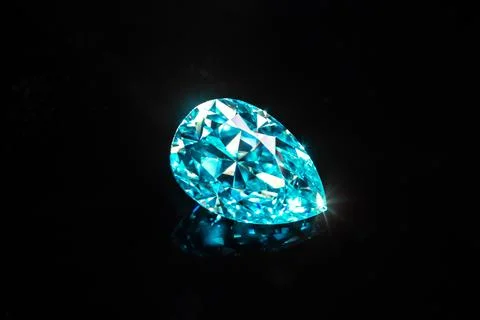 A blue pear shape diamond is sitting on a black surface Stock Photos