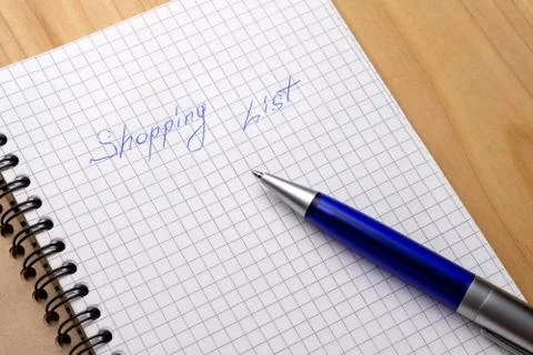 Blue pen on a notebook with sheets in a cage. Sign Shopping List Stock Photos
