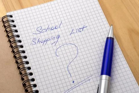 Blue pen on a notebook with sheets in a cage. Sign shopping list and question Stock Photos