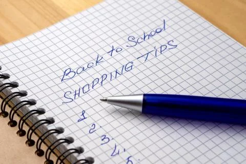 Blue pen on a notebook with sheets in a cage. Sign - back to school and shopp Stock Photos