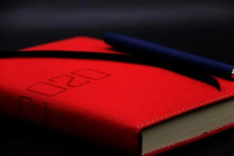 Blue pen on the red notebook 2020 close up,black and gray background Stockfoto's