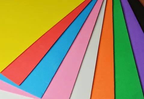 Blue pen with white rests on a stack of colorful foam sheets Stock Photos