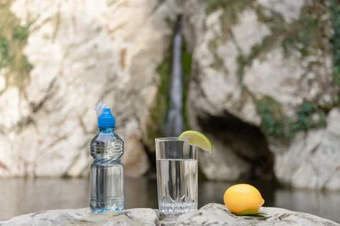 Blue pet-bottle with sport-lock lid and glass of clean water with lemon or li Stock Photos