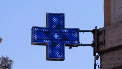 Blue pharmacy cross blinking above a quiet Roman street under clear skies Stock Footage 306319736