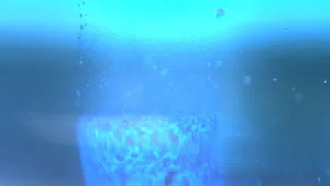 Blue pill dissolving in liquid with many air bubbles. Filmed in slow motion. Video stock 120594504