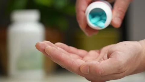 Blue pills fall from the jar onto the hand. The man takes vitamins. Stock Footage 246382335
