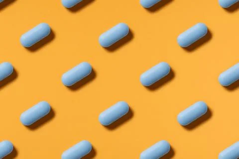 Blue pills lie in rows diagonal on orange background top view copy space pattern Stockfoto's