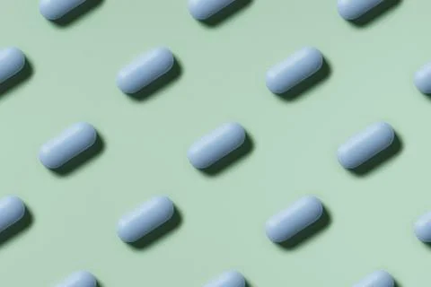 Blue pills lie in rows diagonal on mint green background top view, pattern Stock Photos