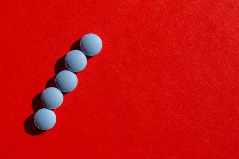 Blue pills on red background Stock Photos