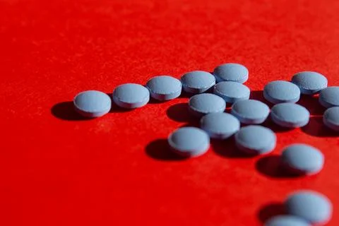 Blue pills on red background Stock Photos