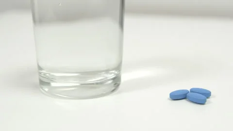 Blue pills for treating erectile dysfunction on a white table with water Stock Footage 274035371