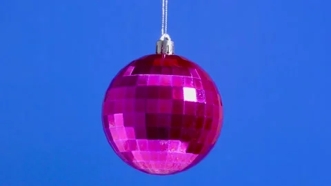 On a blue plain background, a pink Christmas toy ball in a box is spinning Stock Footage 162608231