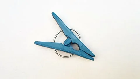 A blue plastic clothes pin or clothes peg for isolated rotating on white Stock Footage 304688136