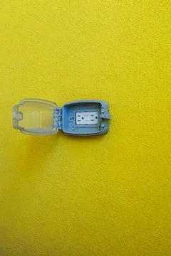 A blue plastic container is attached to a bright yellow wall. The container i Fotos Stock