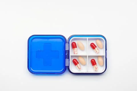 Blue plastic container with different tablets on a white background Stock Photos