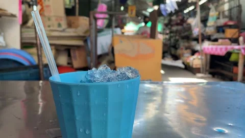 Blue plastic cup with ice and straw on silver table outdoor , Thailand Video stock 232098150