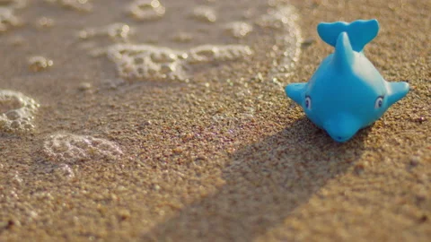 Blue plastic dolphin on the sandy beach at sunset. Stock Footage 196559488