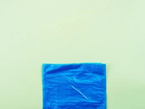 Blue plastic garbage bag roll on green background Stock Photos