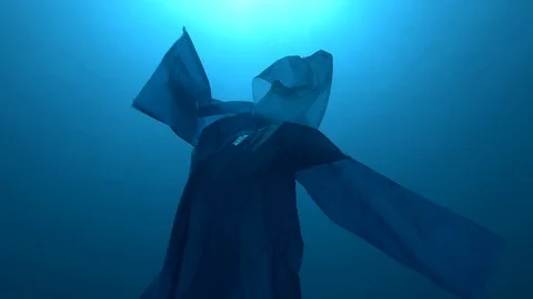 Blue plastic raincoat as a ghost float in the blue water. Plastic pollution Stock Footage 117841548