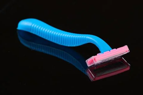 Blue plastic razor on a black background with reflection 库存照片