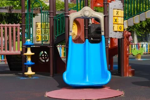 Blue plastic slide on empty multicolored playground Stock-Fotos