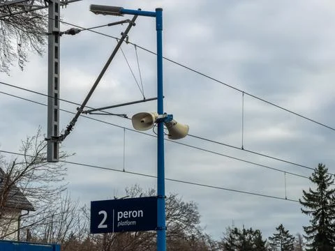 A blue pole stands at a train station platform featuring loudspeakers and an 스톡 사진