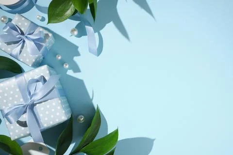 Blue polka dot gift boxes with satin ribbons, green leaves, and pearls on a.. 库存照片