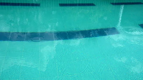 Blue Pool with Raindrops Creating Gentle Ripples on the Water’s Surface Stock Footage 303735316