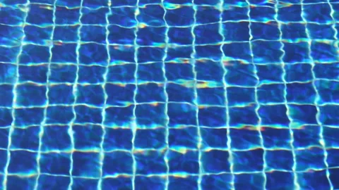 Blue pool tiles appear beneath rippling water with light reflections, filli.. Stock Footage 324892634