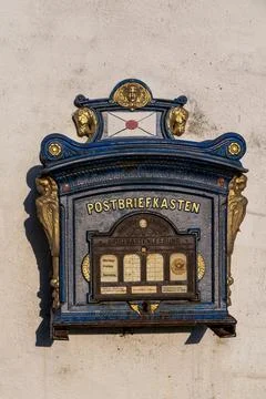 Blue post mailbox on white wall. Stock Photos