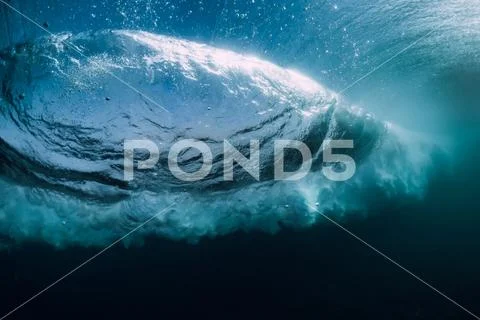Blue powerful wave crashing in ocean. Underwater barrel wave and air bubbles. Stock Photos