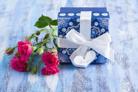 Blue present box and pink roses on wooden tray Stock Photos